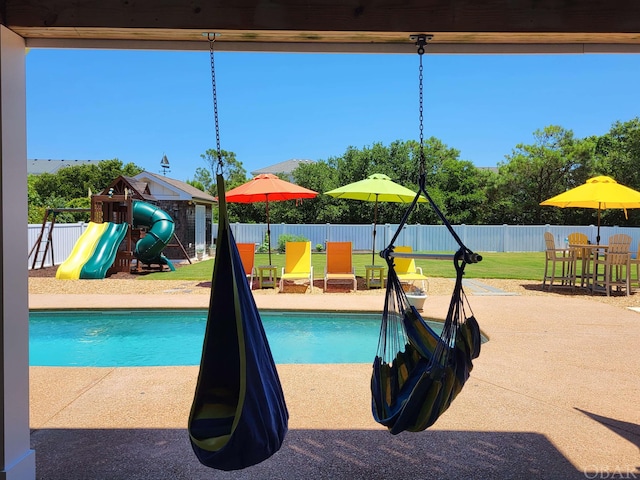 view of pool featuring a lawn, a playground, a fenced backyard, and a fenced in pool