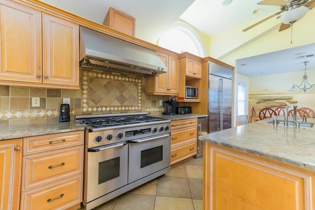 kitchen featuring light tile patterned floors, beverage cooler, stainless steel appliances, a sink, and wall chimney range hood