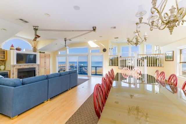 dining area featuring a fireplace, wood finished floors, visible vents, and a notable chandelier