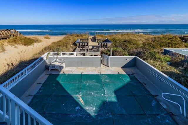 view of swimming pool with a water view, a view of the beach, a fenced in pool, and a patio