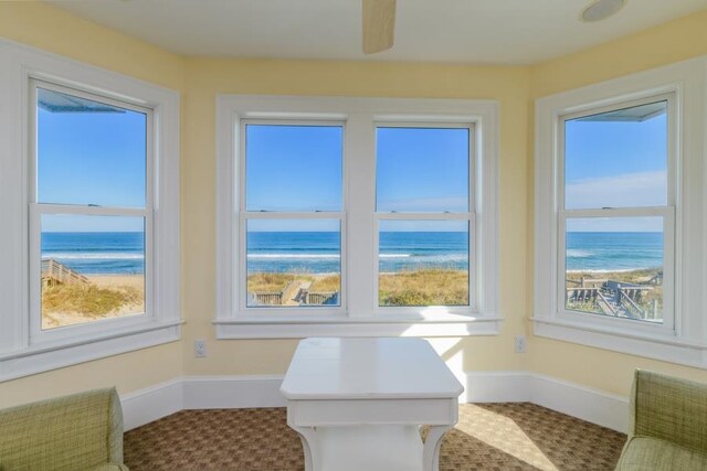 sunroom with plenty of natural light, a beach view, and a water view