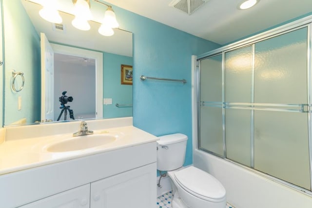 bathroom featuring toilet, visible vents, bath / shower combo with glass door, and vanity