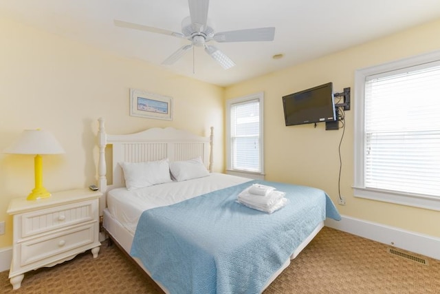 carpeted bedroom featuring a ceiling fan, visible vents, and baseboards