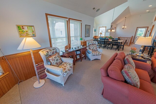 carpeted living area with lofted ceiling, an inviting chandelier, and wood walls