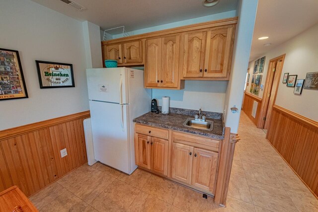 kitchen with visible vents, wainscoting, dark countertops, freestanding refrigerator, and a sink