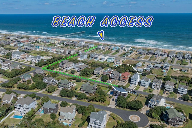 drone / aerial view featuring a water view, a view of the beach, and a residential view