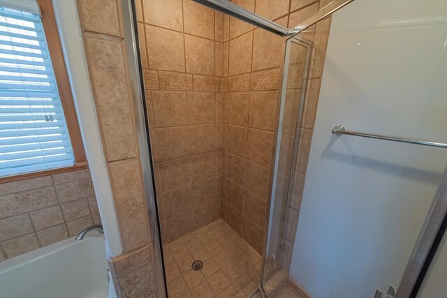 full bath with a healthy amount of sunlight, a garden tub, and a shower stall