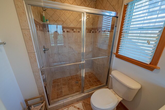 full bath with toilet, a stall shower, and a healthy amount of sunlight