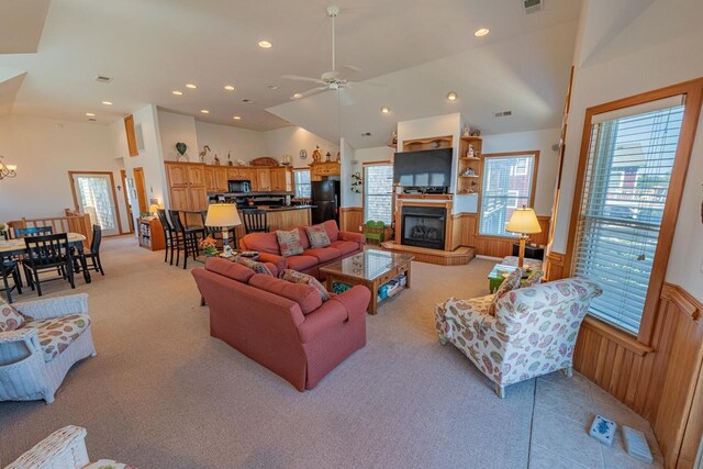 living area with recessed lighting, a fireplace with raised hearth, light carpet, wainscoting, and wood walls