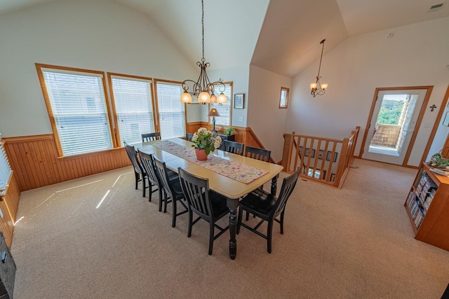 dining space featuring a wainscoted wall, wood walls, light carpet, and an inviting chandelier