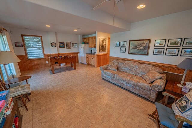 living room with a ceiling fan, recessed lighting, a wainscoted wall, and wood walls