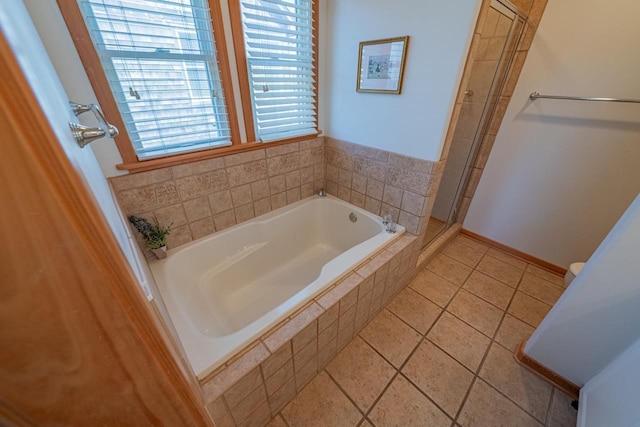 bathroom with a garden tub, a tile shower, and baseboards