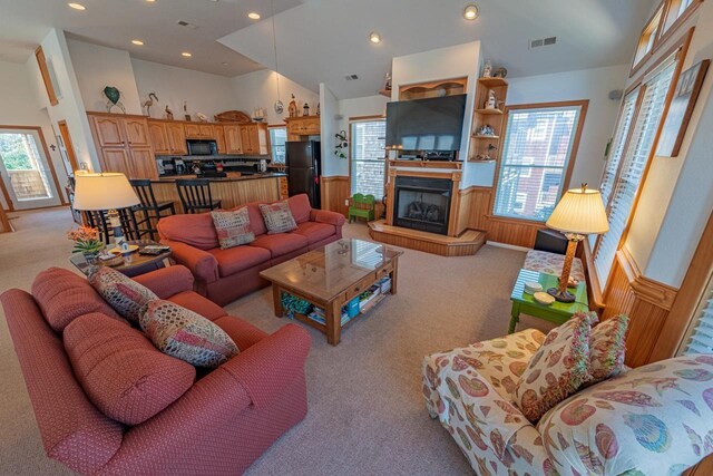 living room featuring light colored carpet, a wealth of natural light, a wainscoted wall, and visible vents