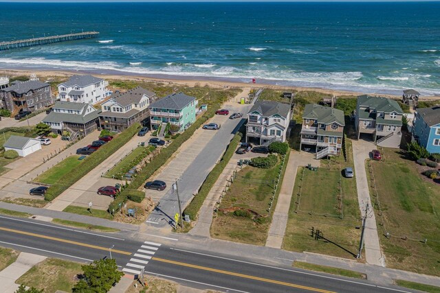 aerial view featuring a view of the beach, a water view, and a residential view