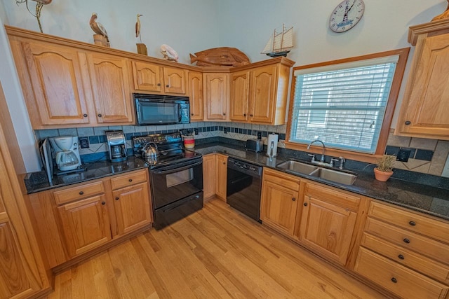 kitchen featuring backsplash, a sink, light wood finished floors, and black appliances