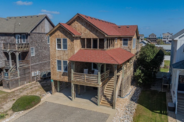 view of front of property with a shingled roof, central AC, a residential view, driveway, and stairs