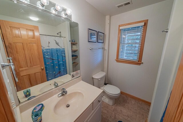 bathroom featuring toilet, vanity, baseboards, visible vents, and tile patterned floors