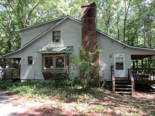 rear view of house featuring a standing seam roof, metal roof, crawl space, and a chimney