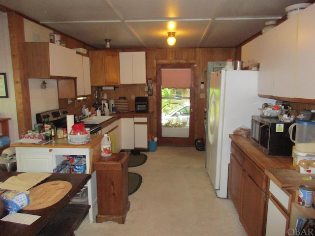 kitchen with light countertops, freestanding refrigerator, stainless steel microwave, and wood walls