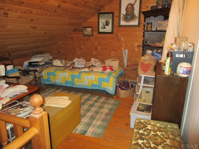 bedroom featuring lofted ceiling, wood walls, and wood finished floors