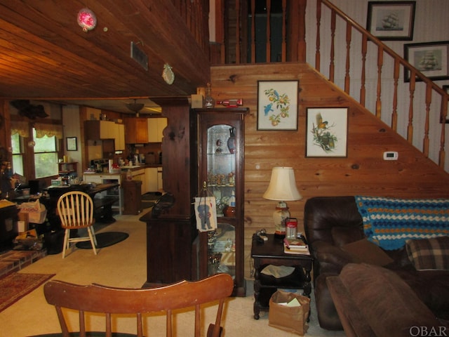 living room with light colored carpet, wooden walls, a high ceiling, and stairs