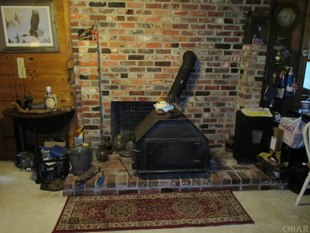 carpeted living room with a wood stove and wooden walls