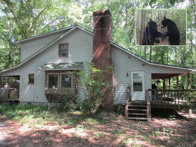 back of house featuring crawl space and a chimney