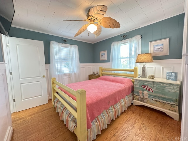 bedroom with light wood finished floors, multiple windows, and crown molding