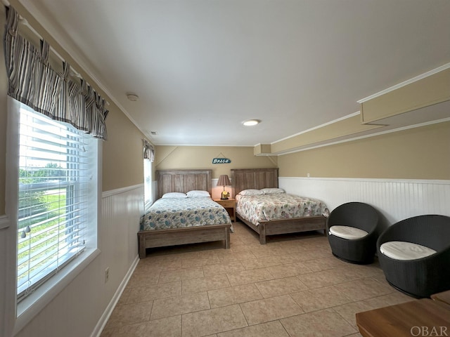 bedroom featuring ornamental molding, wainscoting, and light tile patterned flooring