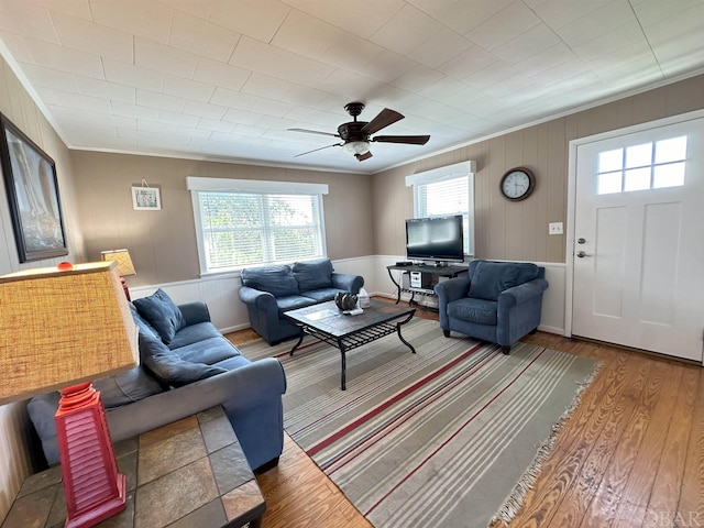 living room with a ceiling fan, ornamental molding, and wood finished floors