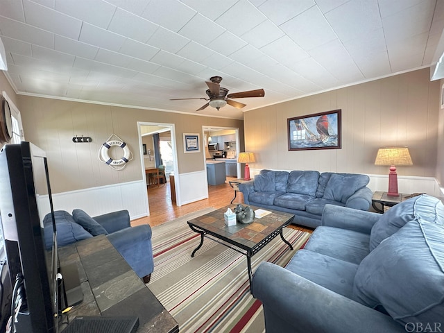 living room featuring a ceiling fan, crown molding, and wood finished floors