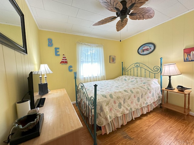 bedroom featuring ornamental molding, a ceiling fan, and wood finished floors