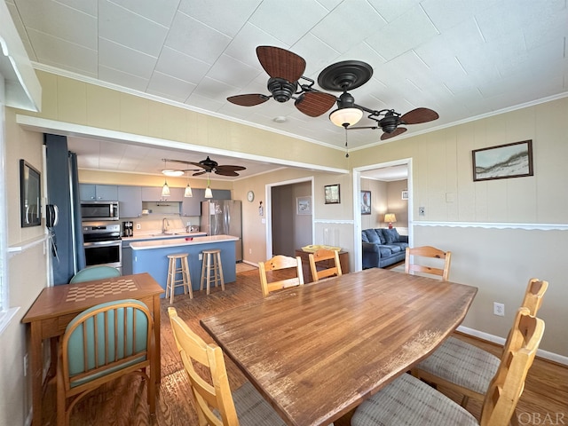 dining room with dark wood-type flooring, ornamental molding, baseboards, and ceiling fan