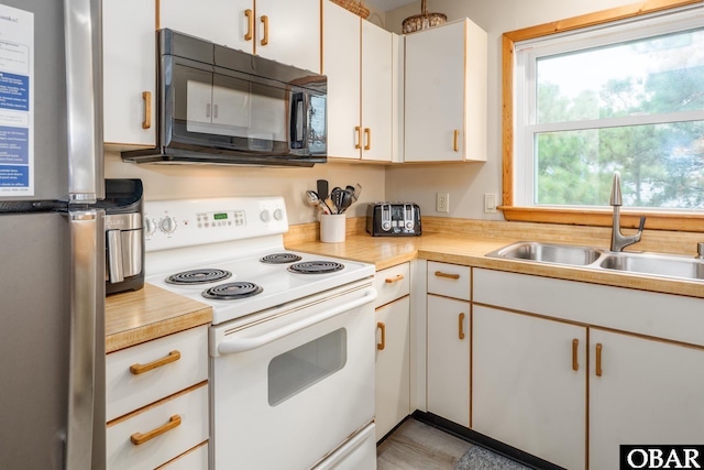 1133 Payson St Lot 120, Corolla, NC 27927 - kitchen with white range with electric cooktop, black microwave, freestanding refrigerator, light countertops, and white cabinets