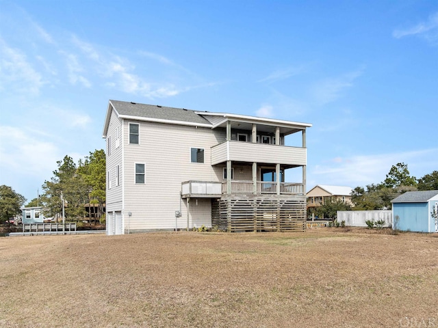 rear view of house featuring an outbuilding, a yard, a shed, and a balcony