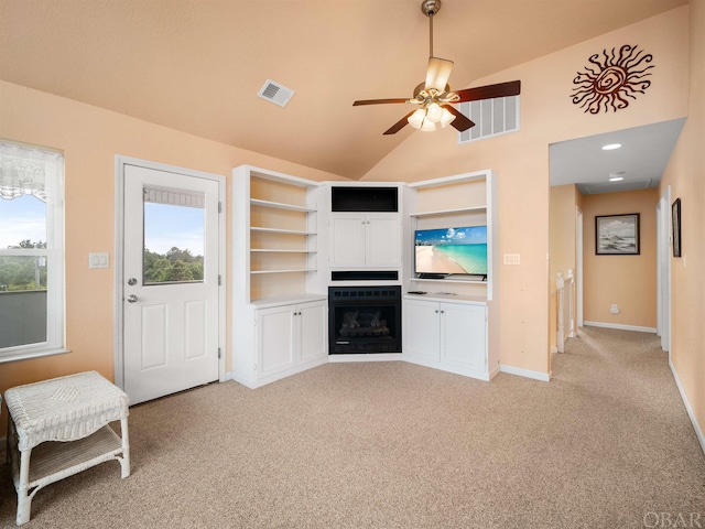 living area with light colored carpet, a wealth of natural light, visible vents, and a fireplace