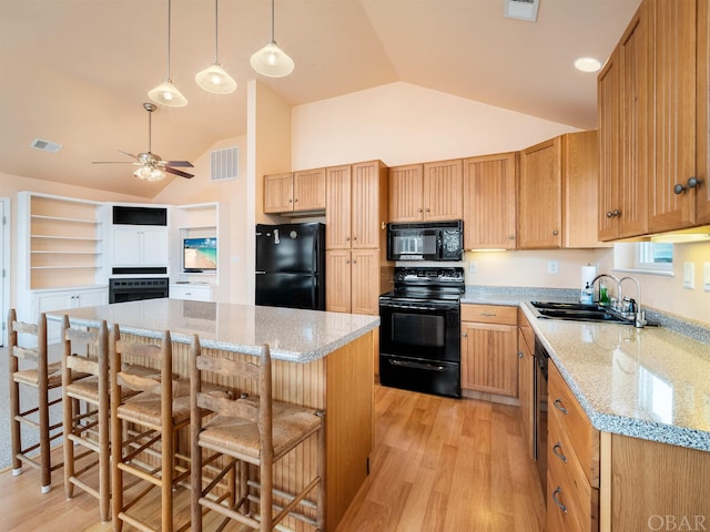 kitchen featuring a kitchen bar, visible vents, a kitchen island, a sink, and black appliances