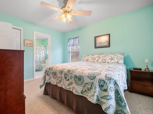 bedroom featuring light carpet, ensuite bath, ceiling fan, and baseboards