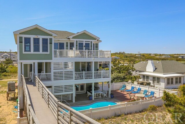 rear view of house with a patio, a fenced backyard, a balcony, central air condition unit, and a shingled roof