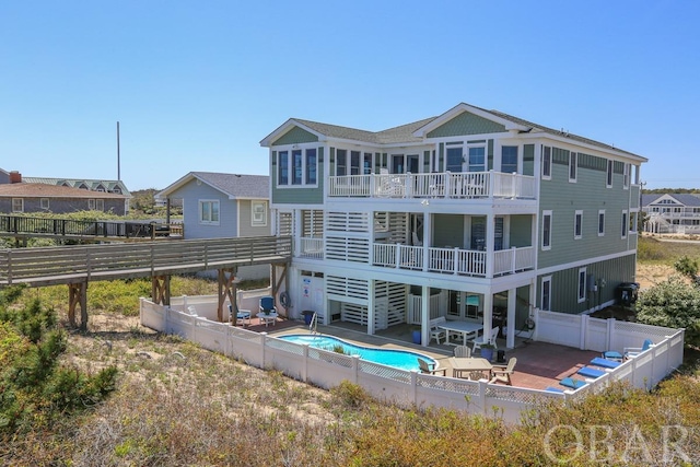 rear view of property with a balcony, a patio area, a fenced backyard, and a fenced in pool