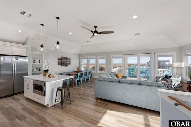 kitchen with visible vents, open floor plan, white cabinetry, appliances with stainless steel finishes, and vaulted ceiling