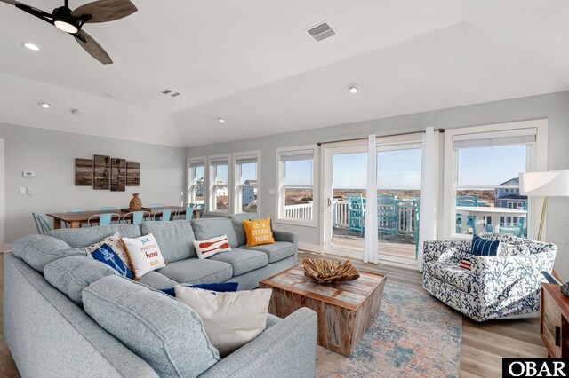 living room with visible vents, light wood-style flooring, ceiling fan, and vaulted ceiling