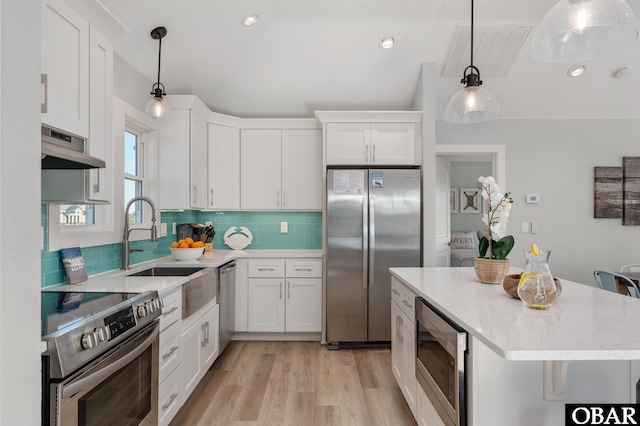 kitchen with light wood finished floors, backsplash, under cabinet range hood, white cabinets, and stainless steel appliances