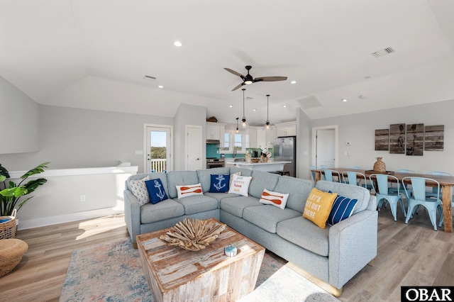 living area with light wood finished floors, visible vents, a ceiling fan, and lofted ceiling