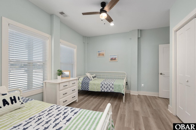 bedroom with visible vents, a ceiling fan, a closet, light wood-style floors, and baseboards