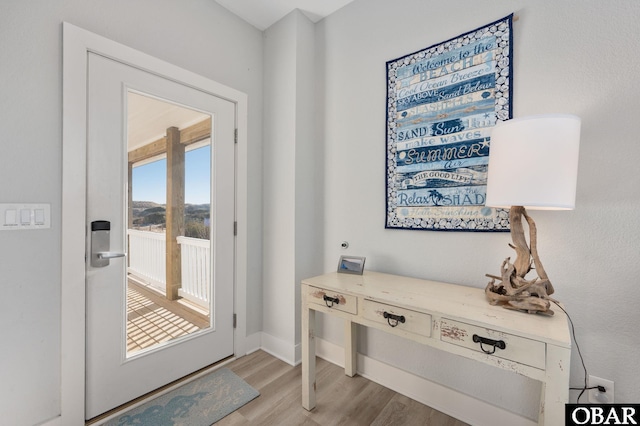 doorway featuring light wood-type flooring and baseboards