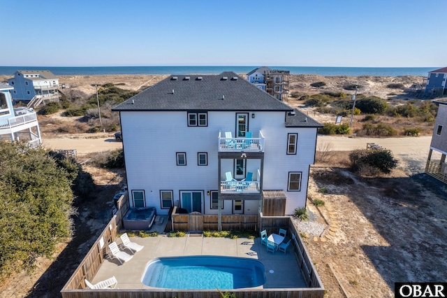 rear view of property with a fenced in pool, fence, a water view, a balcony, and a patio