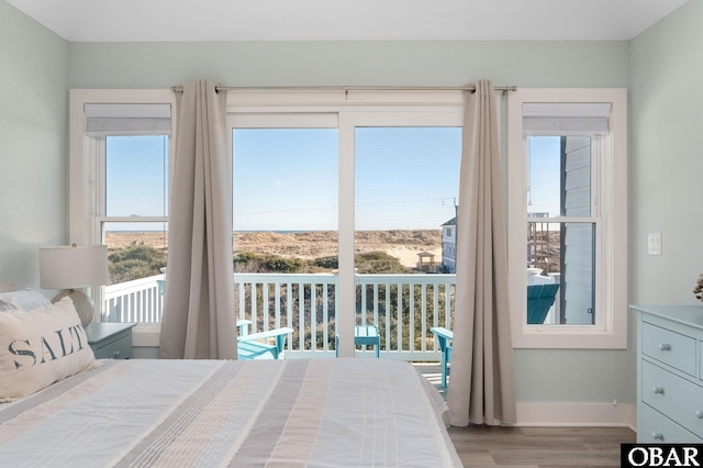 bedroom with baseboards, wood finished floors, and access to exterior