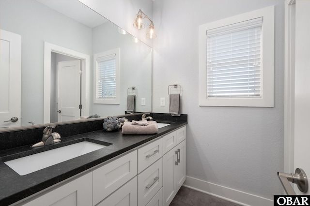 bathroom featuring a sink, baseboards, and double vanity