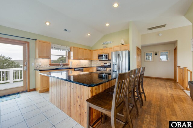 117 Four Seasons Ln Lot 12, Duck, NC 27949 - kitchen featuring light brown cabinets, appliances with stainless steel finishes, a breakfast bar, decorative backsplash, and lofted ceiling